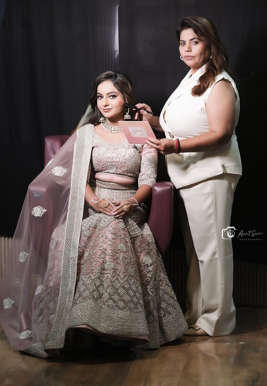 Bharti standing beside a client in a pale lehenga, both facing the camera in the studio.