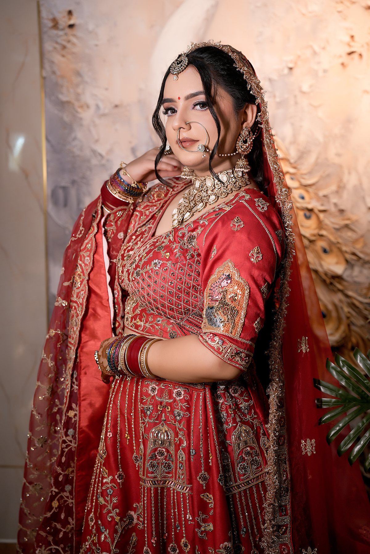 A bride in red, finished, standing against a soft painted backdrop.