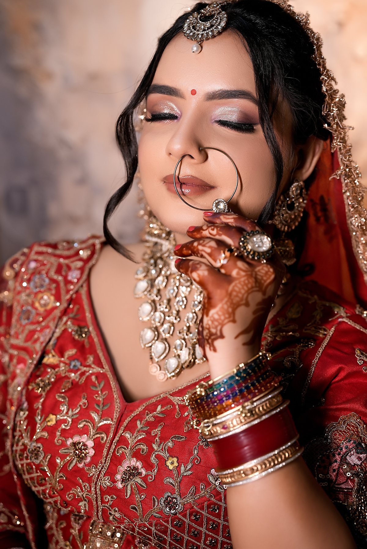 A bride with her eyes closed, nath and kundan choker, eye makeup finished.